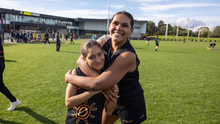 A female footy player hugs another player on field