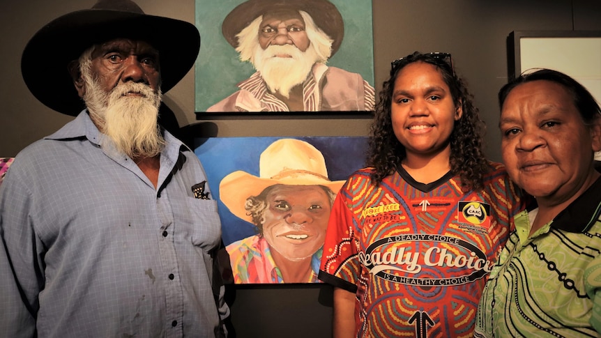 A woman stands with portraits and her family.