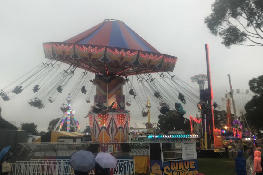 Riders on the Wave Swinger ride at Perth Royal Show's Sideshow Alley fly around in the rain.