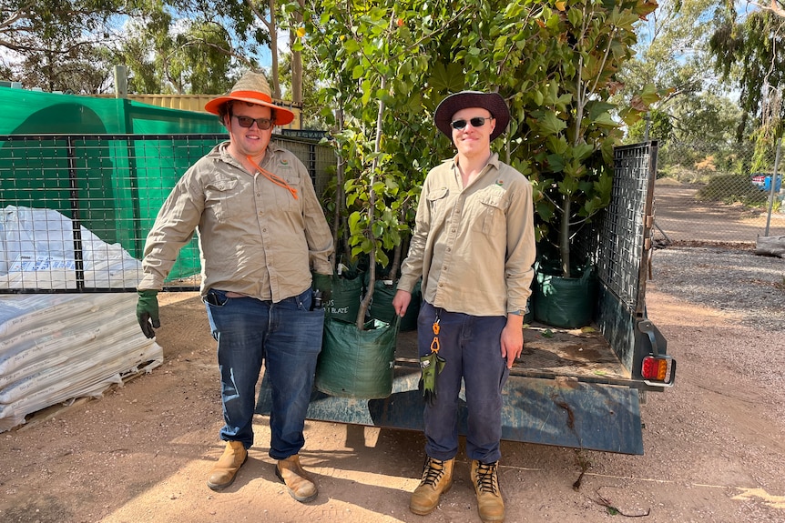 Jack Knight and Matt Smith work together to carry a large plant that has just been taken off a trailer