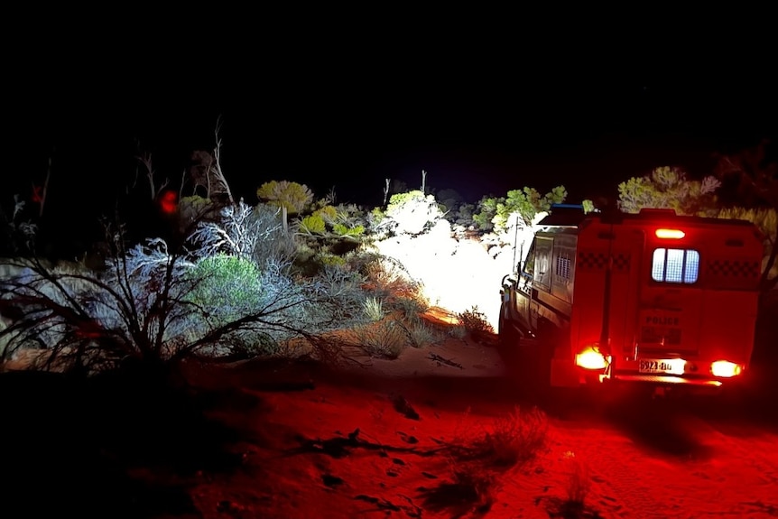 A police car rescuing two stranded travellers in the South Australian outback. 