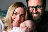 Anna Meares and her partner Nick Flyger smile and cradle their baby daughter Evelyn.