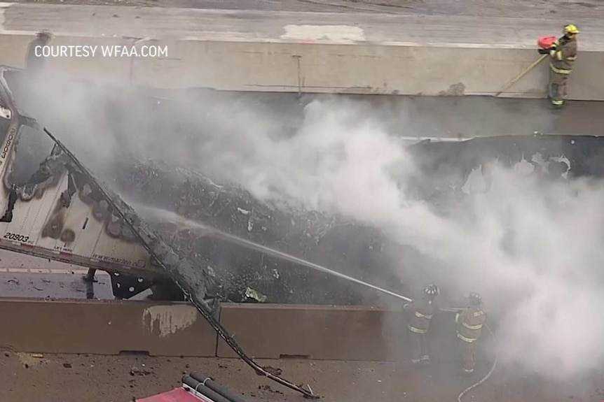 firefighters extinguish a fire on a charred avocado truck.