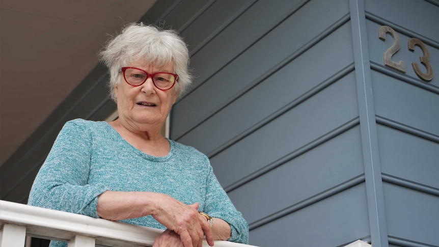 An elderly woman outside a house