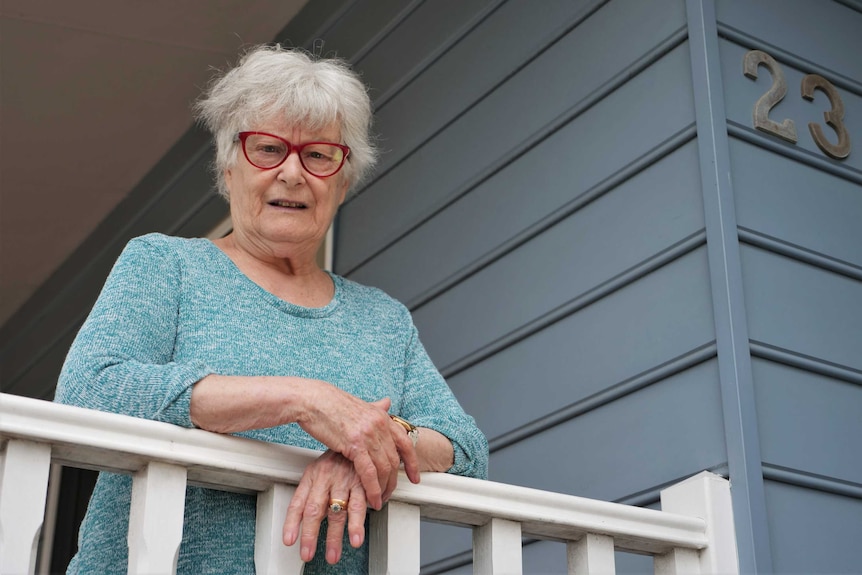 An elderly woman outside a house