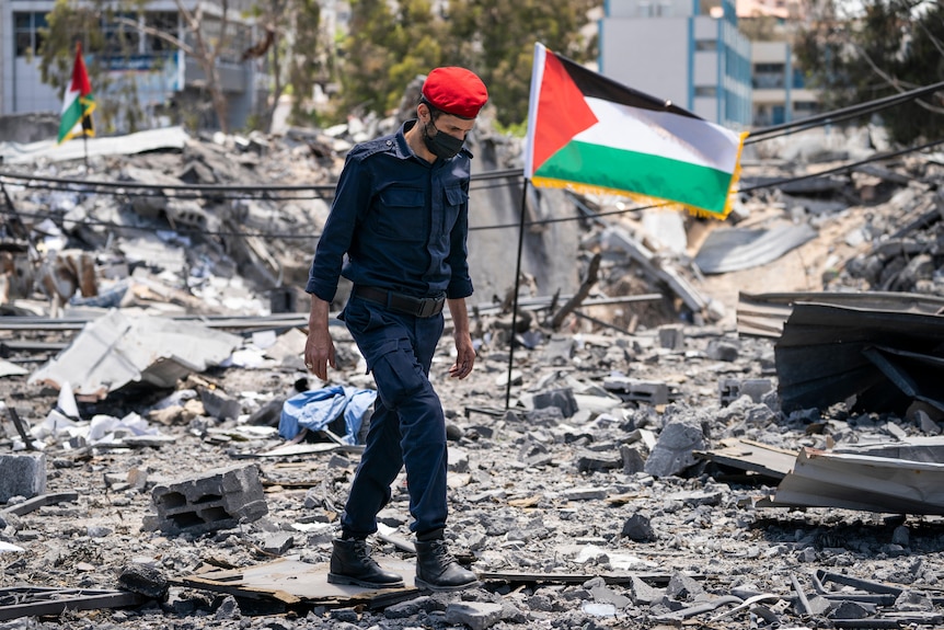 Hamas police walk through debris from a destroyed station building hit by an Israeli air strike