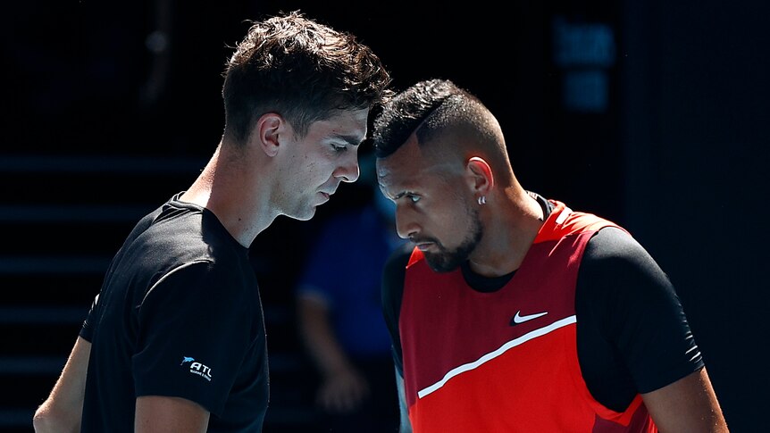Two Australian tennis players look down at the court.