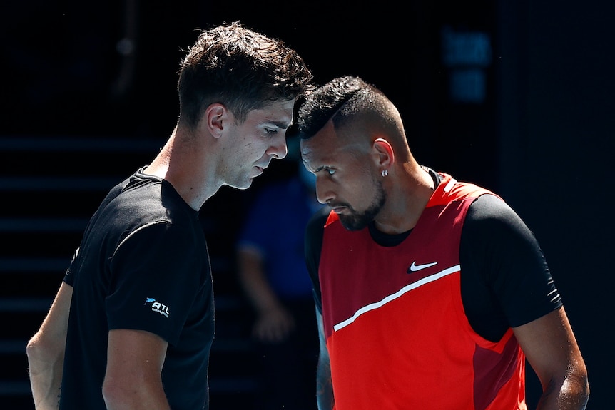 Two Australian tennis players look down at the court.