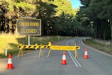 Road closed sign and road closed barriers across bitumen road 