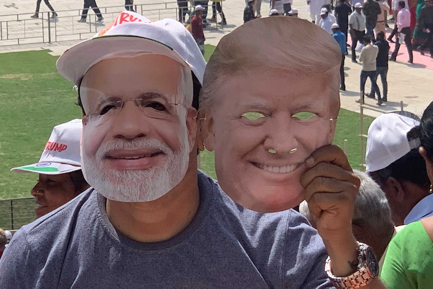 A person wears Narendra Modi's mask and holds Donald Trump's mask.