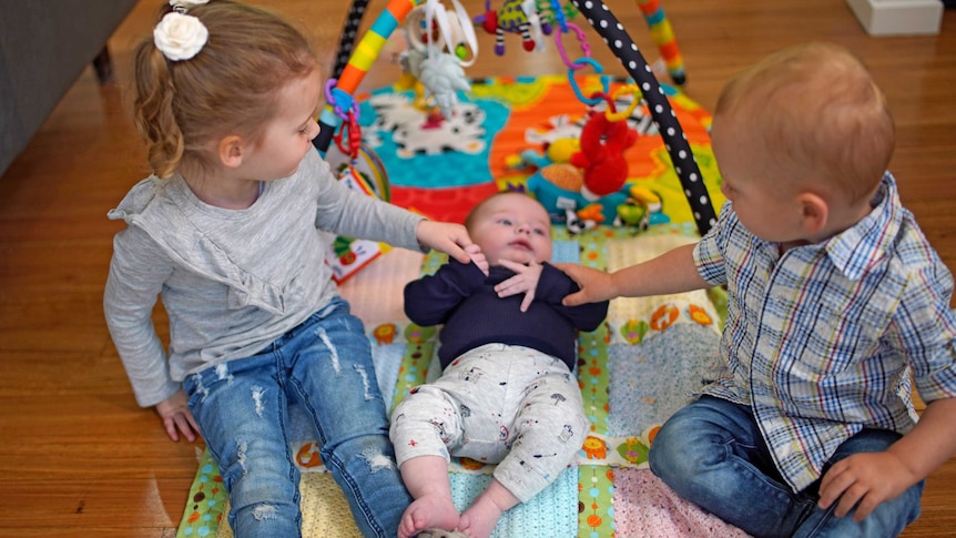 Three children play on a baby playmat