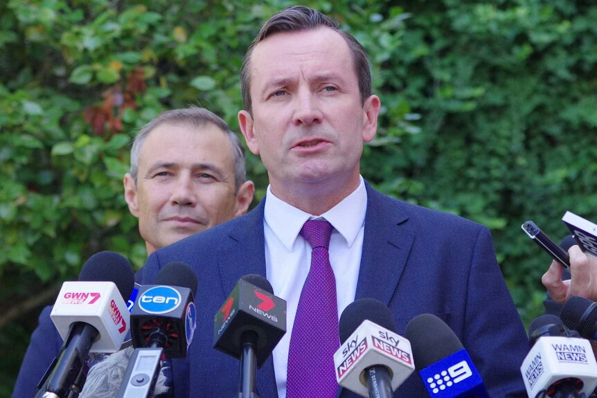 A mid-shot of Mark McGowan talking into microphones at a media conference outdoors.