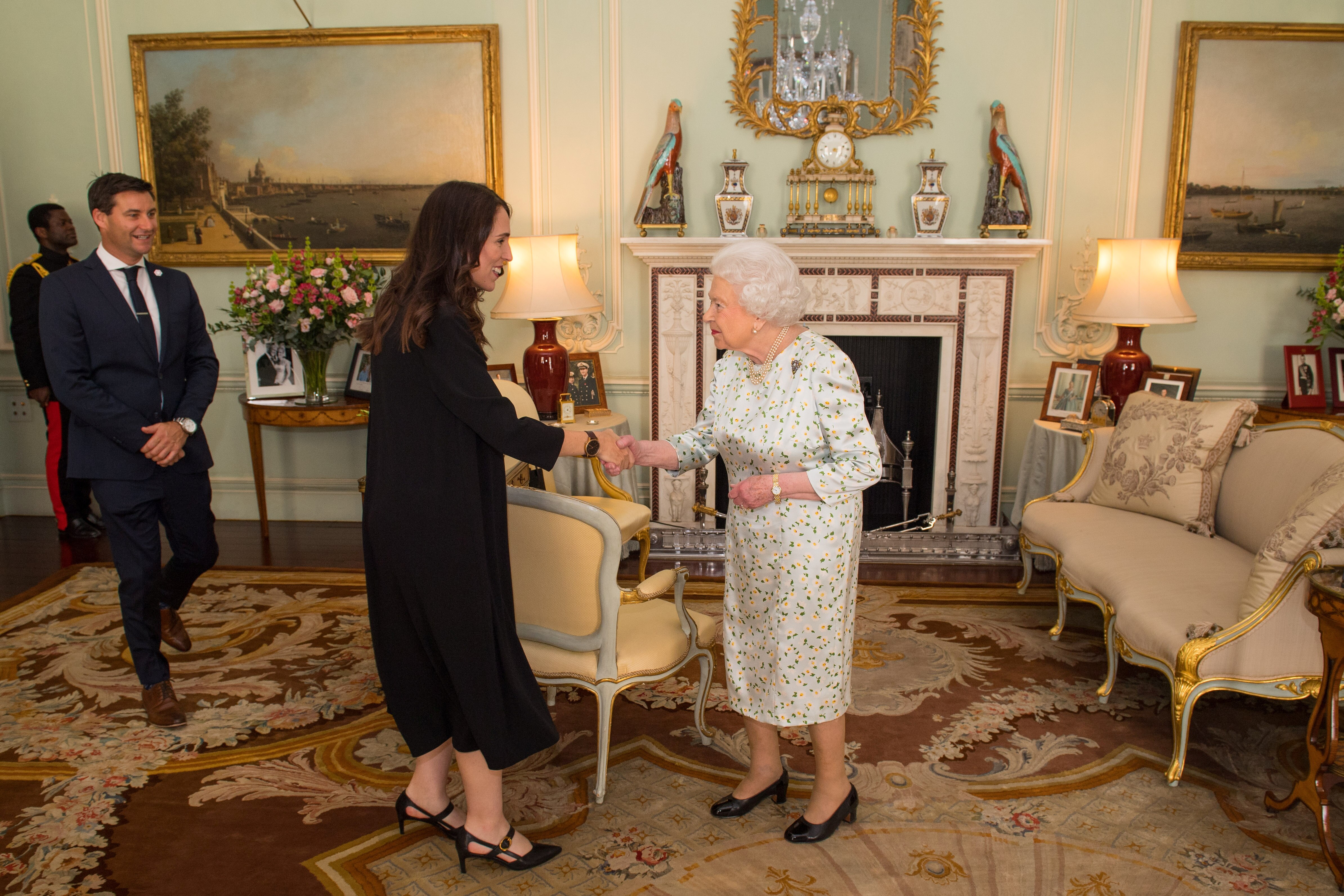 Two women, former New Zealand prime minister Jacinda Ardern and Queen Elizabeth, shake hands.