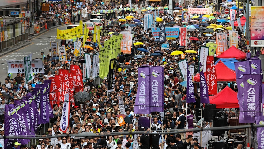 Protesters carrying flags and umbrellas march on street