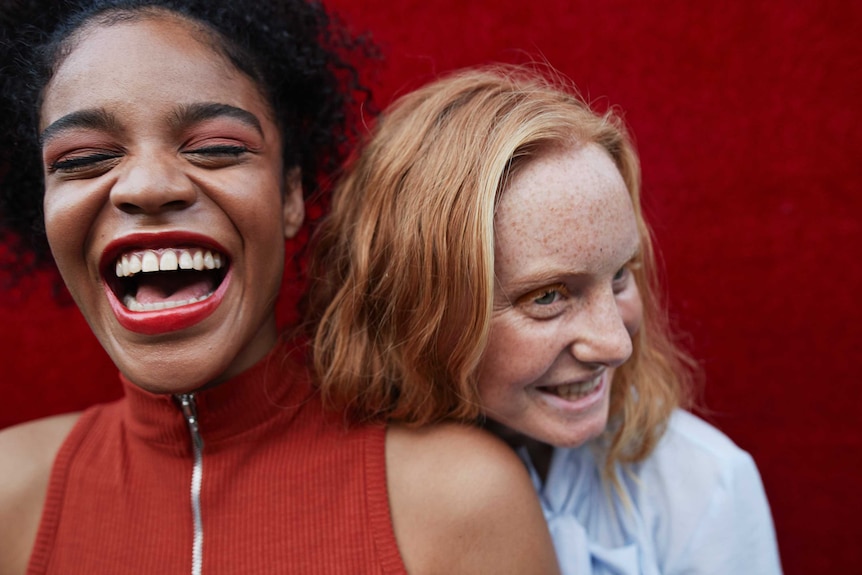 A close up of two young women laughing and smiling.