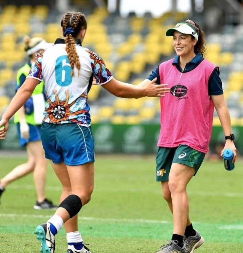 Emilee Cherry high fives a player while on the rugby union field.