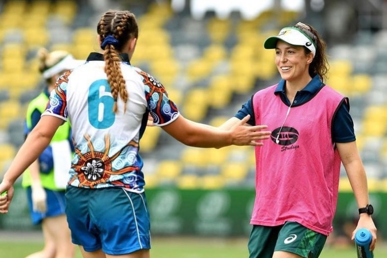 Emilee Cherry high fives a player while on the rugby union field.