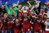 Liverpool's Jordan Henderson lifts a trophy with his team mates cheering in the background