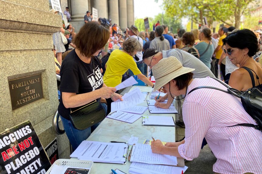 People sign petitions at an anti-vaccination protest on the steps of South Australia's Parliament.