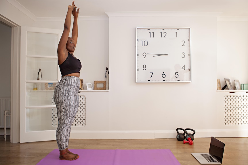 Woman of colour exercising at home in front of laptop