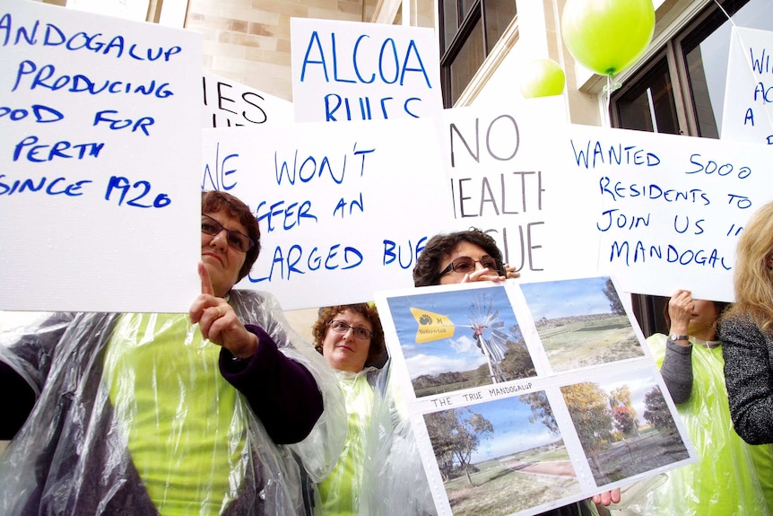 Mandogalup residents hold hand made signs protesting the buffer zone