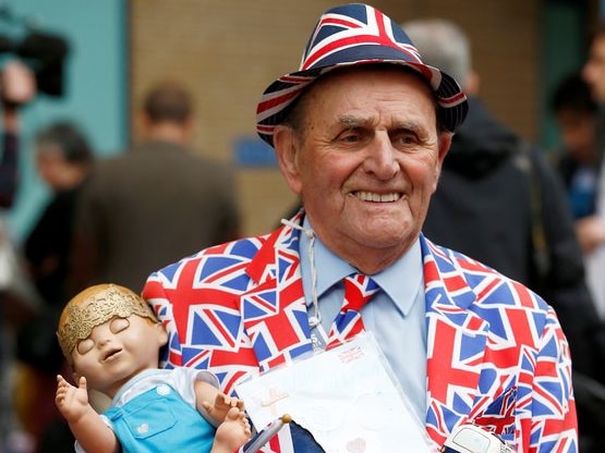 A supporter of the royal family, dressed head to toe in union jacks, holds a doll wearing a crown
