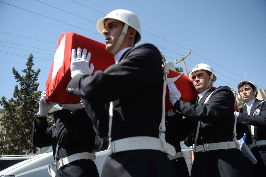 Turkish police officers carry the coffin of one of two officers shot dead at home