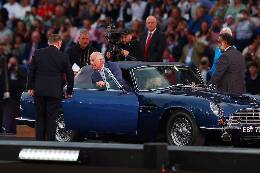 Prince Charles gets out of a blue Aston Martin