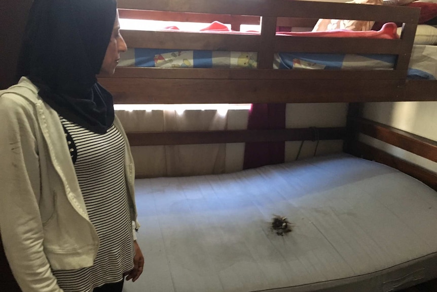 Woman looking at a burnt mark on bed where hoverboard was charging before it exploded and caught fire.