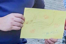 A drawing of a rat on yellow paper with red love hearts around it