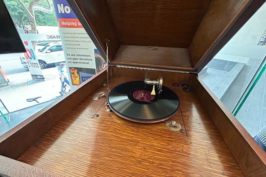 The inside of a timber gramophone with a record playing in the middle.