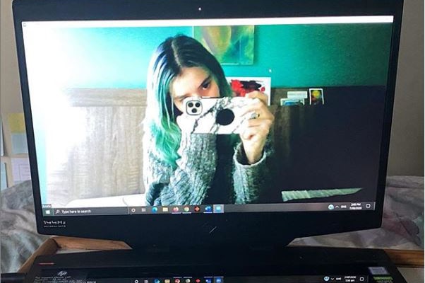 A woman is seen taking a photo on a computer screen