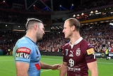 Two men talk to each other on the field after a rugby league match