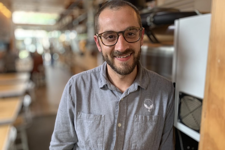 Andrew stands near a coffee roasting machine at his business in Gardenvale, Melbourne ahead of the 2022 federal election. 