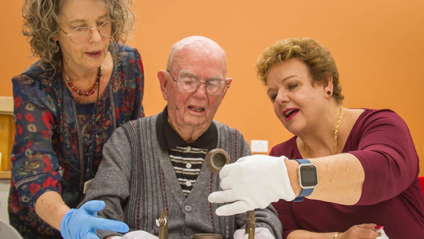 Queensland Museum curator Tracy Ryan, Ben Blunderfield and daughter Rosslyn look at the inkwell.