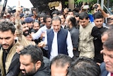 Pakistan's former Prime Minister Imran Khan walks through a crowd of people before appearing in court