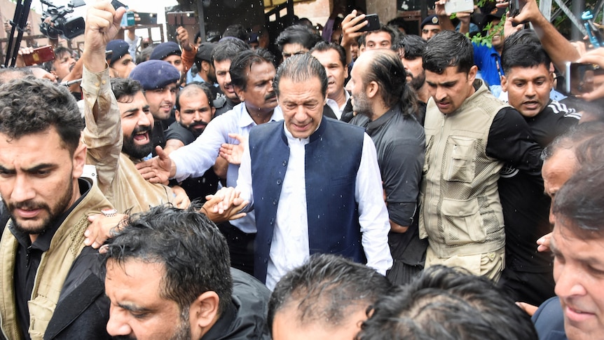 Pakistan's former Prime Minister Imran Khan walks through a crowd of people before appearing in court