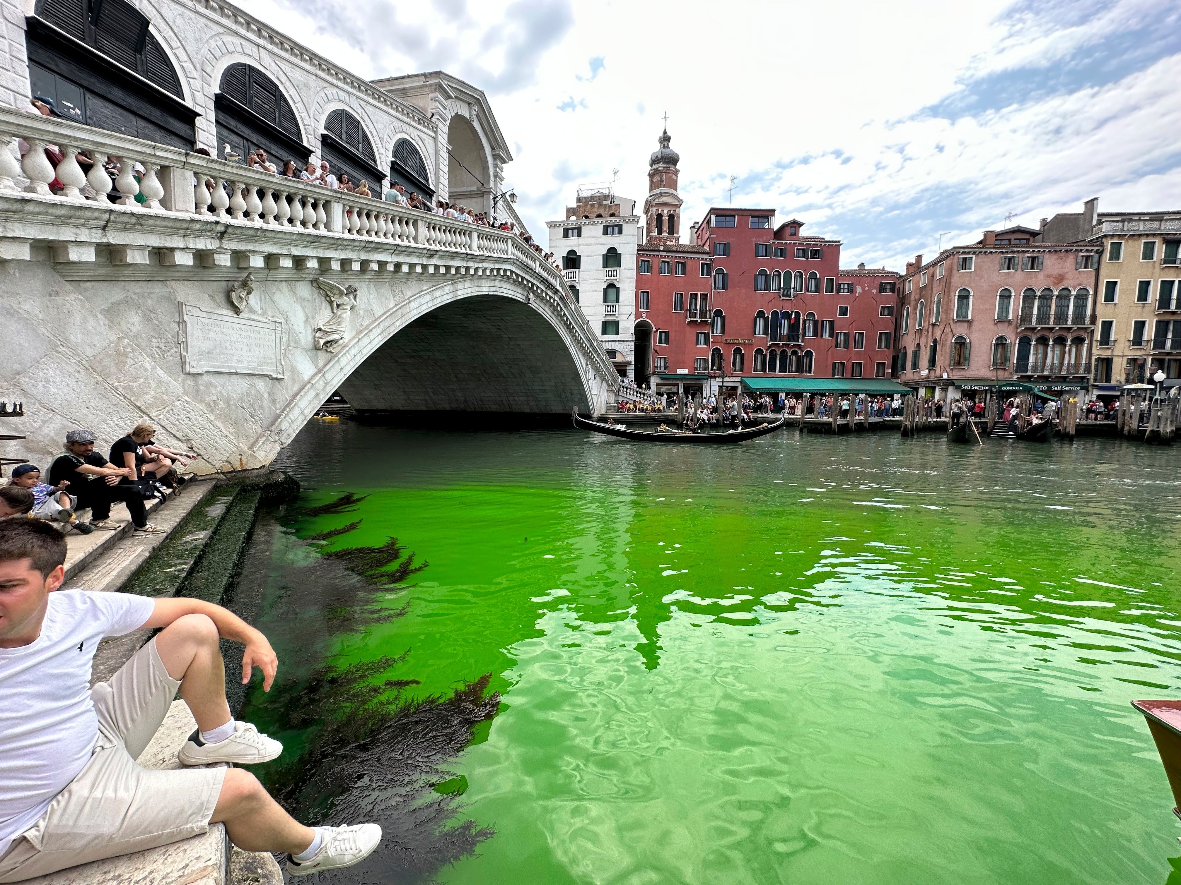 A bridge over a river canal with bright green water. 