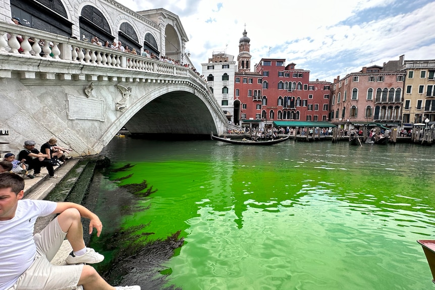 A bridge over a river canal with bright green water. 