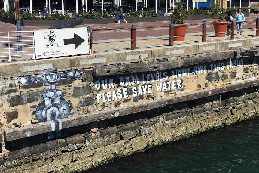 A mural above the harbour that says "our dam levels won't rise this easily, please save water"