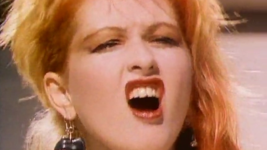 Cyndi Lauper in the music film clip for Girls Just Wanna Have Fun. Her eyes are closed and mouth curled