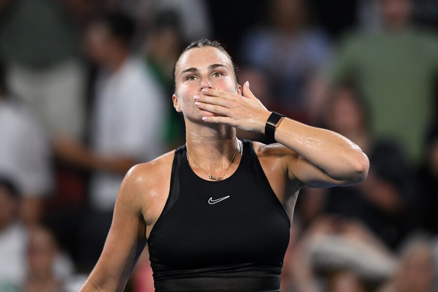 Aryna Sabalenka holding her hand to her mouth looking suprised. 