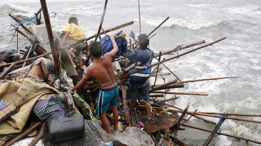 Family attempts to salvage items from home damaged by Typhoon Koppu