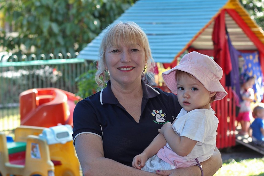 A female childcare worker holds a baby