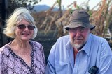 Denise and Tony Welch look at the camera with burnt lychee and banana trees behind them