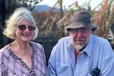 Denise and Tony Welch look at the camera with burnt lychee and banana trees behind them