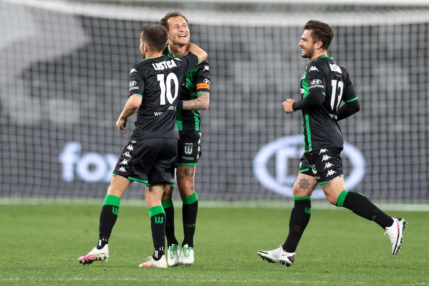 Three Western United A-League players celebrate a goal in their elimination final against Brisbane Roar.