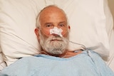 A man in a hospital bed with a tube going into his nose.