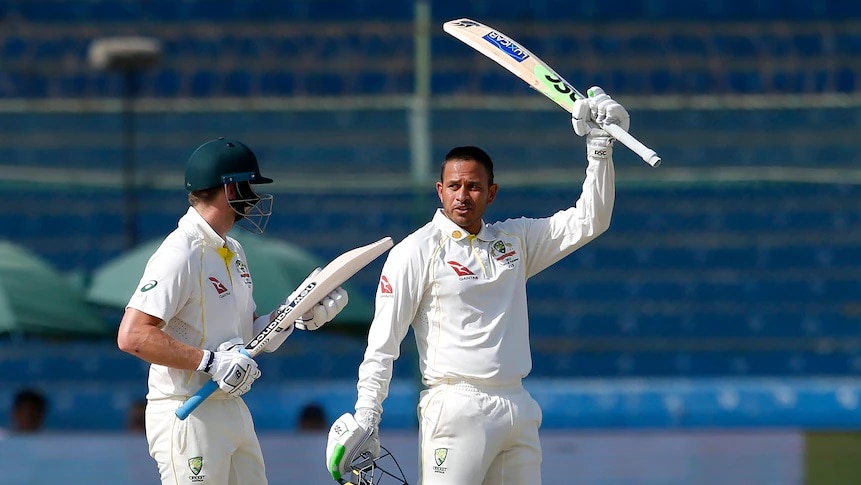 Australian batter Usman Khawaja waves his bat in celebration after scoring a century in Karachi