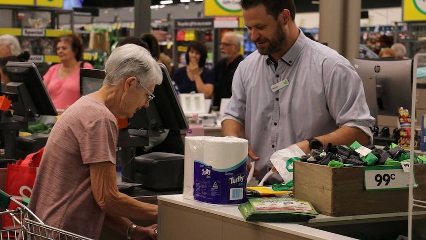 An older woman at a checkout in a supermarket